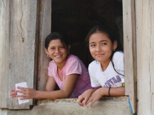 Zwei Mädchen schauen beim Fenster heraus